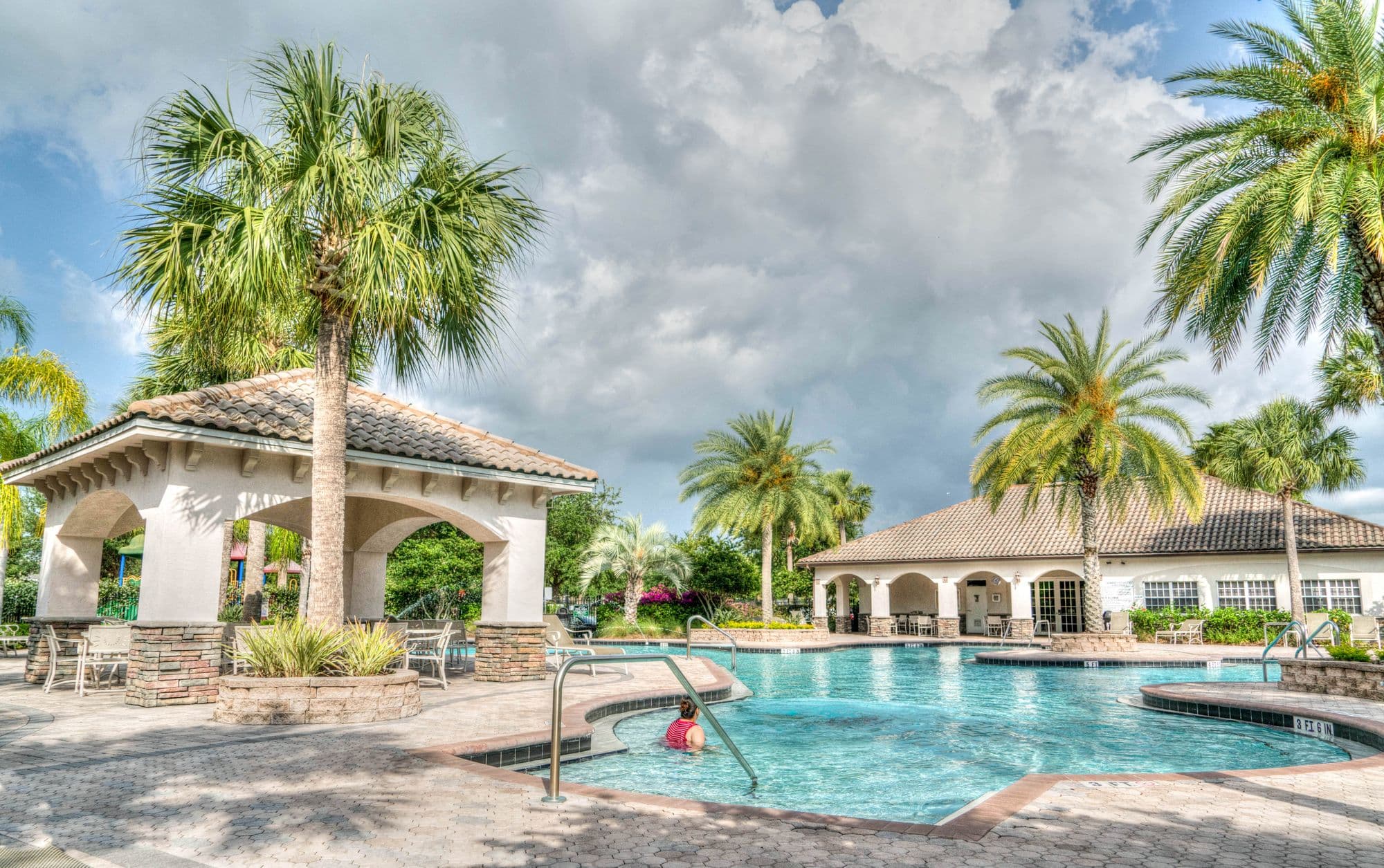 Community clubhouse pool and pavilion under palm trees