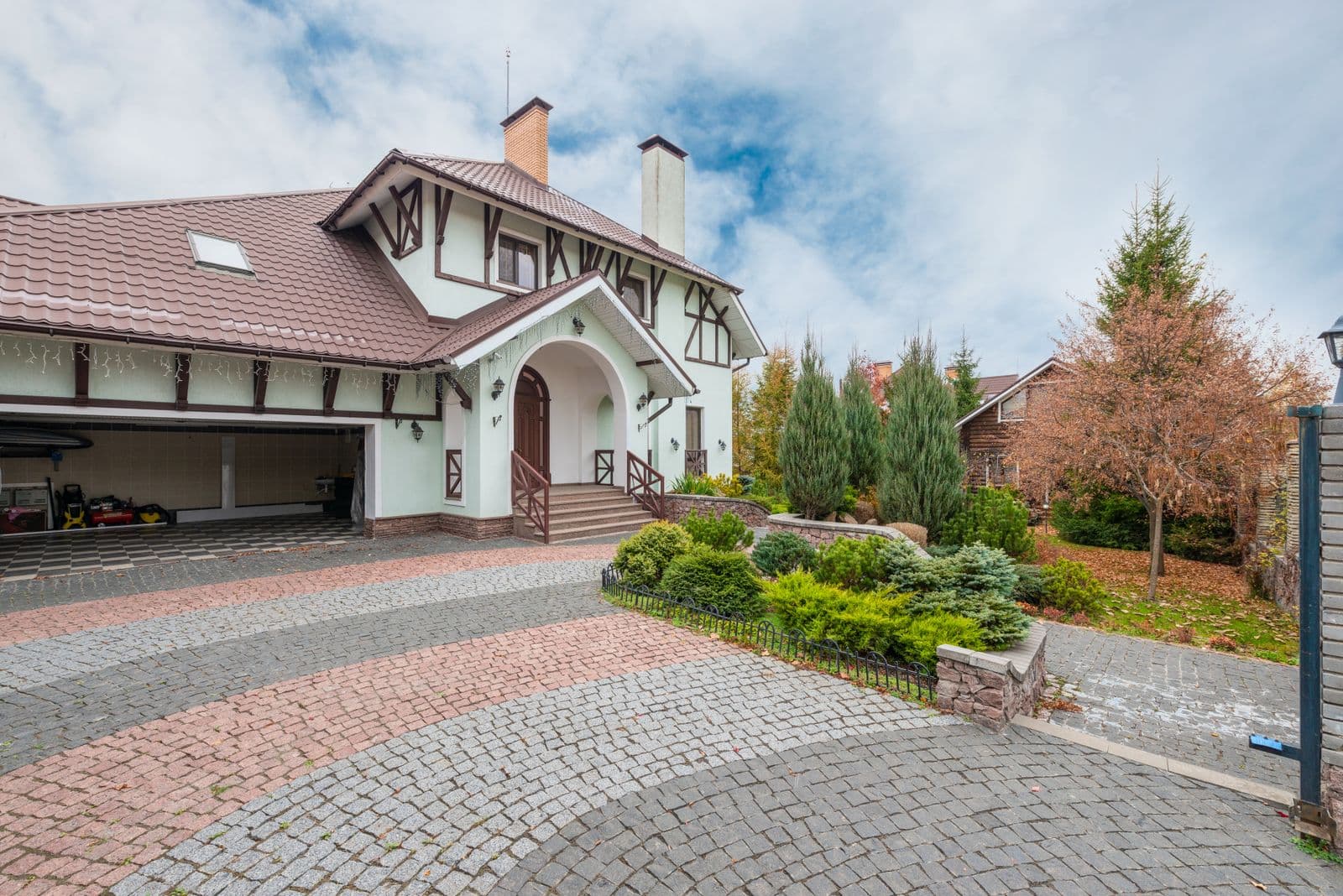 Home with a patterned paver driveway and landscaped entry