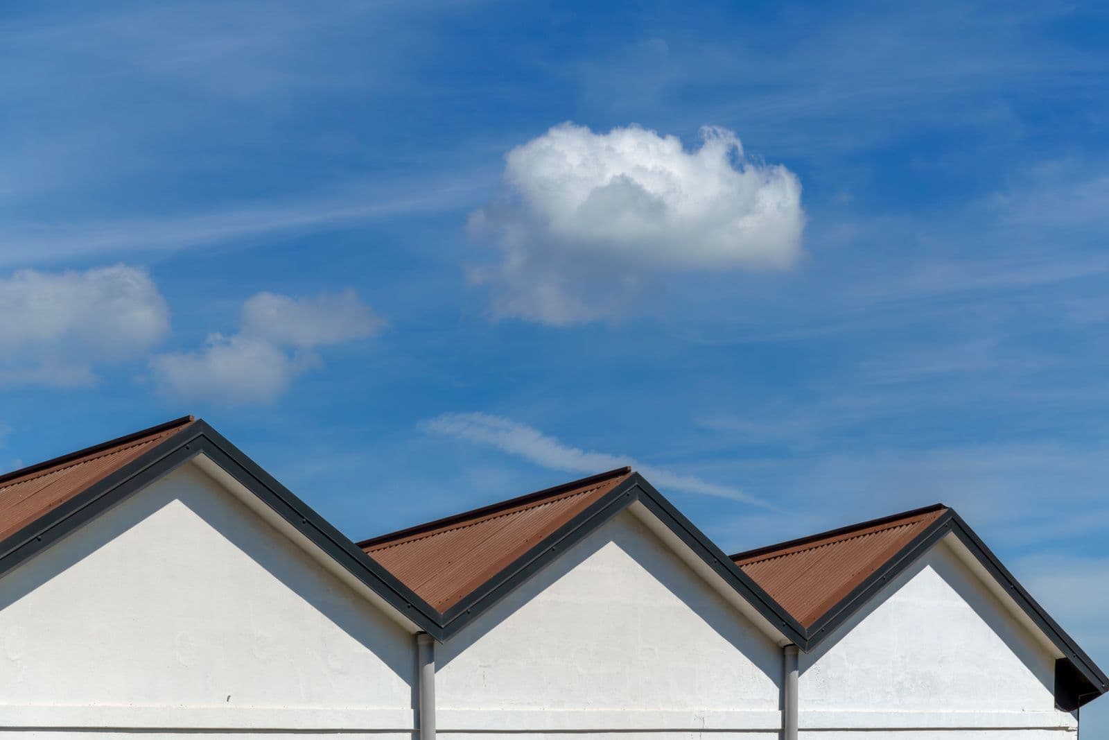 Clean gabled metal rooflines against a bright blue sky